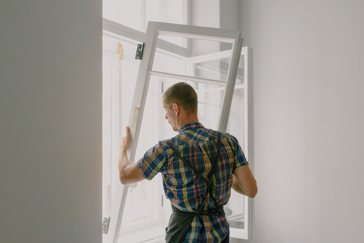 Vakman tilt een raamvleugel met glas uit het kozijn
